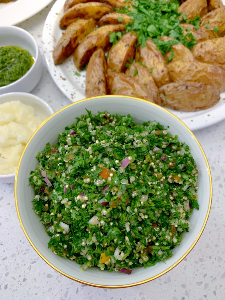 A bowl of bright green, fluffy quinoa tabbouleh.
